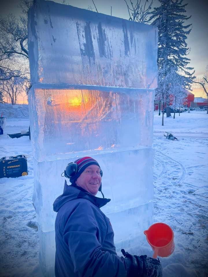 Sculptor stacking ice blocks at sunrise