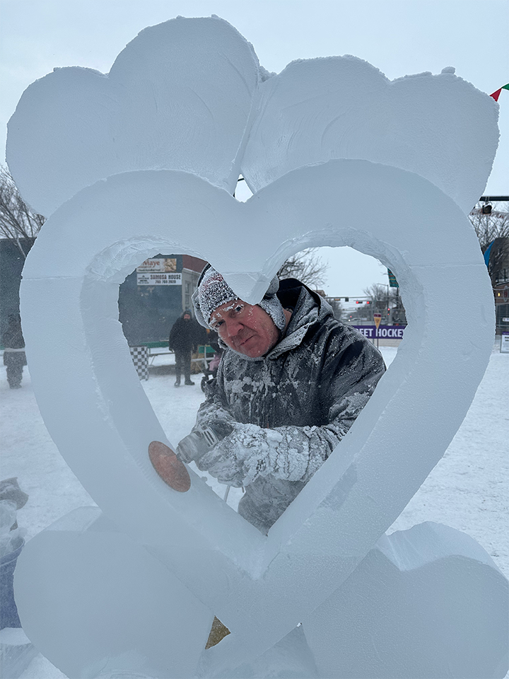 Sculptor framed in heart ice sculpture in progress